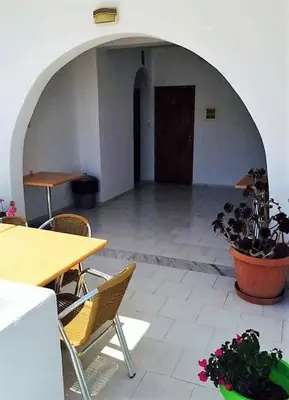 a room with a table and chairs and a table and a plant at Protopapas Rooms in Loutro