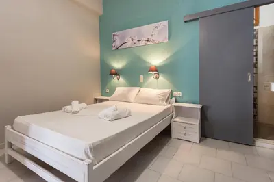 a bedroom with a large bed with white sheets at Protopapas Rooms in Loutro