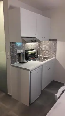 a white kitchen with a sink and a counter top at Niriides in Almirida