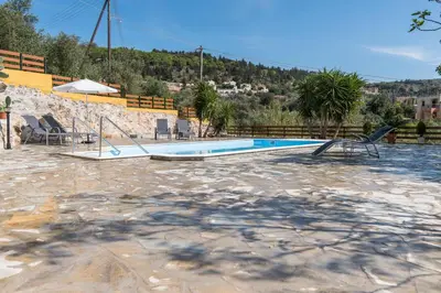 a swimming pool with two chairs next to it at Dekem Residence in Gavalochori