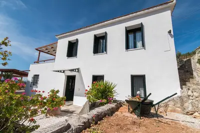 a white house with black windows and flowers at Dekem Residence in Gavalochori