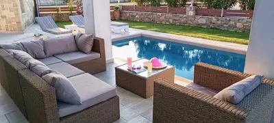 a patio with wicker furniture next to a swimming pool at Villa Alexandros in Kissamos