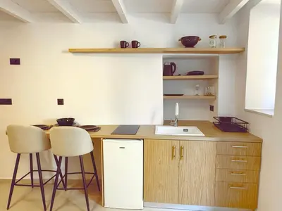 a kitchen with a sink and two bar stools at Sotoportego in Chania Town