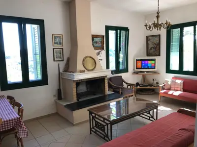 a living room with a fireplace and a red couch at Temenia House in Teménia