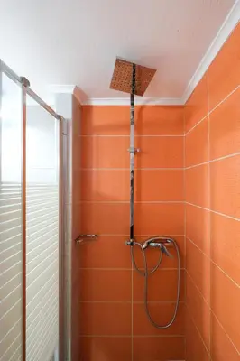 a shower in a bathroom with an orange wall at Arocaria Apartments in Chania Town