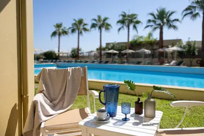 a table and chair next to a swimming pool at Giannoulis - Santa Marina Plaza (Adults Only) in Agia Marina Nea Kydonias