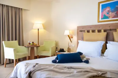 a hotel room with a bed and two chairs and a table at Giannoulis - Santa Marina Plaza (Adults Only) in Agia Marina Nea Kydonias