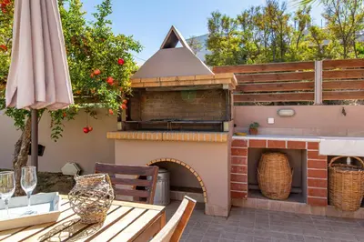 an outdoor pizza oven with a table and an umbrella at Rea's Sea House in Kato Galatas