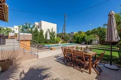a patio with a table with chairs and an umbrella at Rea's Sea House in Kato Galatas