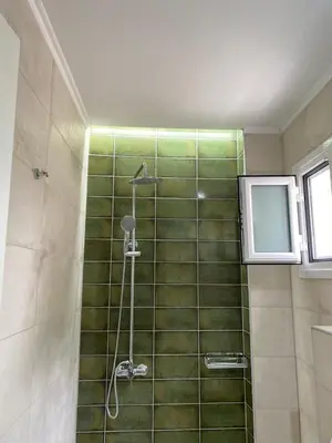 a bathroom with a shower with green tile at Faros Rooms in Loutro