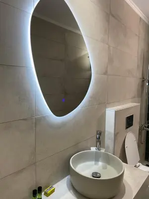 a bathroom with a sink and a round mirror at Faros Rooms in Loutro