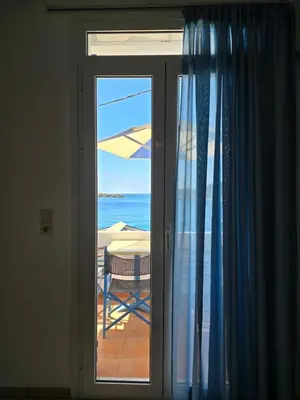 a sliding glass door with a view of the ocean at Faros Rooms in Loutro
