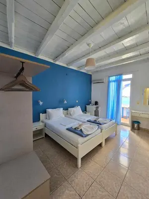 a bedroom with a large bed with a blue wall at Faros Rooms in Loutro