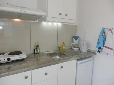 a white kitchen with a sink and a microwave at Maro Suites in Tavronitis