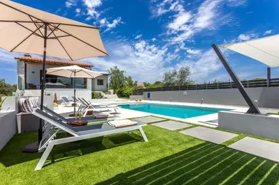 a backyard with a pool and a patio furniture with an umbrella at Villa Ampelaki - Premium Villa with heated pool in Kounoupidhianá