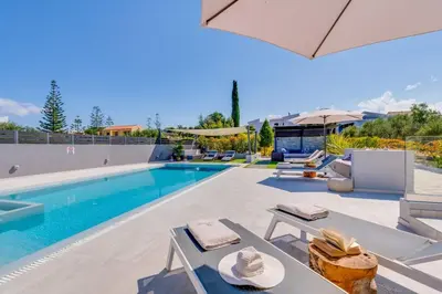 a swimming pool with chairs and umbrellas next to a pool at Villa Ampelaki - Premium Villa with heated pool in Kounoupidhianá