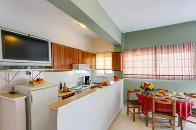 a kitchen with a table and a tv on the wall at Agapi Studios in Kato Daratso