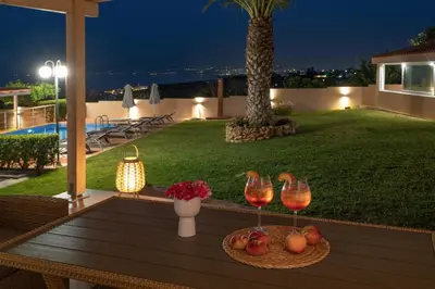 a table with two glasses of wine and fruit on a patio at Villa Aretousa 1 in Agia Marina Nea Kydonias
