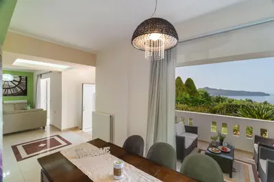 a dining room with a table and a large window at Villa Aretousa 1 in Agia Marina Nea Kydonias