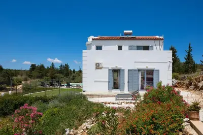 a white house on a hill with flowers at Villa di Lusso Agave con Piscina Privata Riscaldata e Jacuzzi in Litsárdha