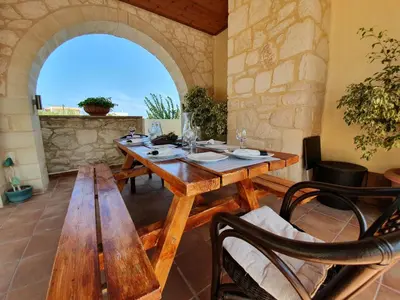 a dining room with a wooden table and benches at Argo Villa Kalives in Kalyves