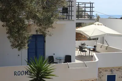 a view of a white building with a table and umbrella at John Akroyiali in Loutro