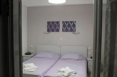 a white bed with purple sheets in a room at John Akroyiali in Loutro