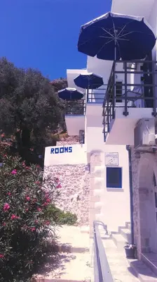 a white building with umbrellas on top of it at John Akroyiali in Loutro