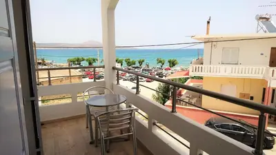 a balcony with a table and chairs and a view of a city at Crown Apartments in Kalyves