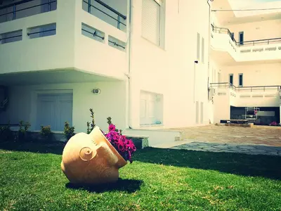 a flower pot sitting in the grass next to a building at Crown Apartments in Kalyves