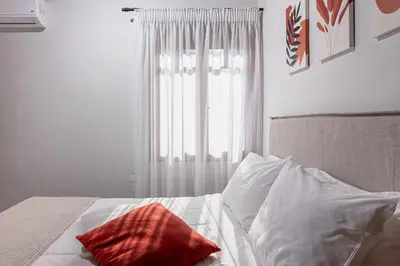 a white bed with a red pillow and a window at Alia Stone Villa-Ideal for families-Heated pool in Nohia