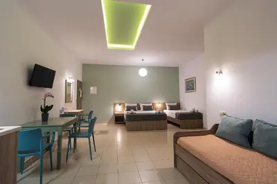a living room with a couch and a bed and a table at Nicole Rooms in Palaiochóra