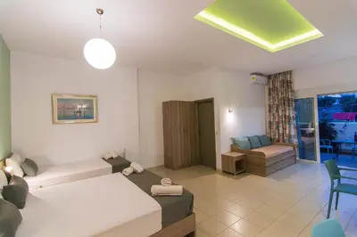 a room with two beds and a living room at Nicole Rooms in Palaiochóra