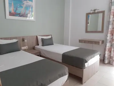 a hotel room with two beds and a mirror at Nicole Rooms in Palaiochóra
