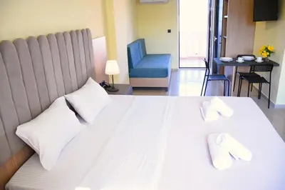 a bedroom with a large white bed with a blue chair at Eden Beach Hotel in Agia Marina Nea Kydonias