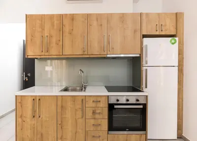 a kitchen with wooden cabinets and a white refrigerator at Castell Hotel in Kissamos