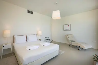 a white bedroom with a white bed and two chairs at Blue Sea Luxury Villa in Maleme