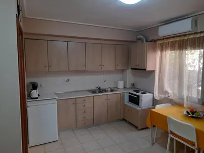 a kitchen with wooden cabinets and a sink and a table at Nikos Studio in Kalyves