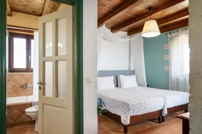a bedroom with a bed and a bathroom at Stone Built Private villa Emerald with pool, 30m to Beach & BBQ! in Ropanianá