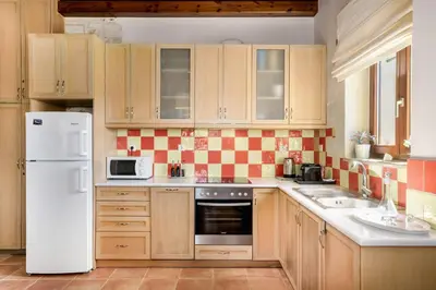 a kitchen with wooden cabinets and a white refrigerator at Stone Built Private villa Emerald with pool, 30m to Beach & BBQ! in Ropanianá