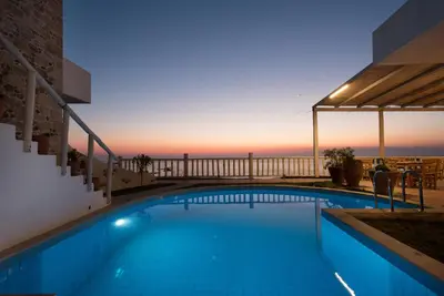 a swimming pool with a view of the ocean at dusk at Elia in Kavoúsion