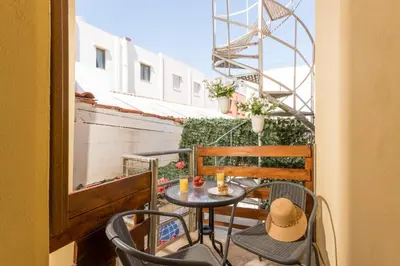 a table and chairs on a balcony with a hat at Porto Orion Studios in Chania Town