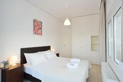 a white bedroom with a large bed and a window at Kalamaki Apartments in Kalamaki Chanion