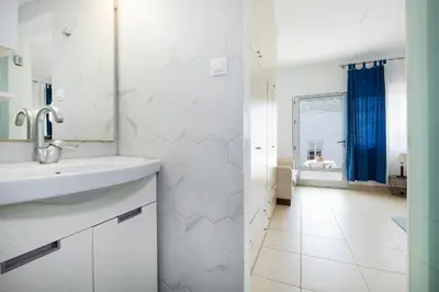 a white bathroom with a sink and a mirror at Irini House in Arménoi