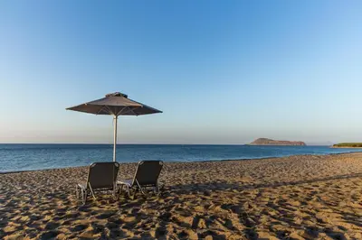 two chairs and an umbrella on a beach at Electra Studios in Gerani Chanion