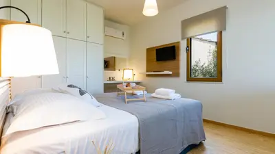 a white bedroom with a bed and a table at Villa Staride, sea view, private heated pool, playground in Païdhokhórion