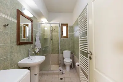 a bathroom with a toilet and a sink and a shower at Villa Staride, sea view, private heated pool, playground in Païdhokhórion