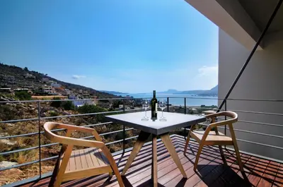 a table with a bottle of wine and two chairs on a balcony at Seametry Luxury Living Apartments ADULTS ONLY in Souda
