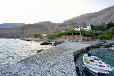 a small boat on the shore of a body of water at Taverna Akrogiali in Loutro