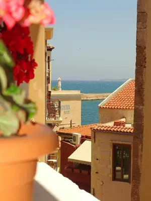 a vase of flowers on a balcony with a view of the ocean at Anemones Rooms in Chania Town